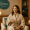 A woman in a spa robe smiling and holding a glass of water in the Genesis Medspa relaxation lounge.